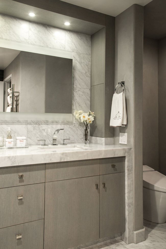 A rectangular mirror is flanked by two narrow counter-to-ceiling medicine cabinets